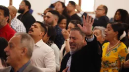 Men and women worship with raised hands during the service
