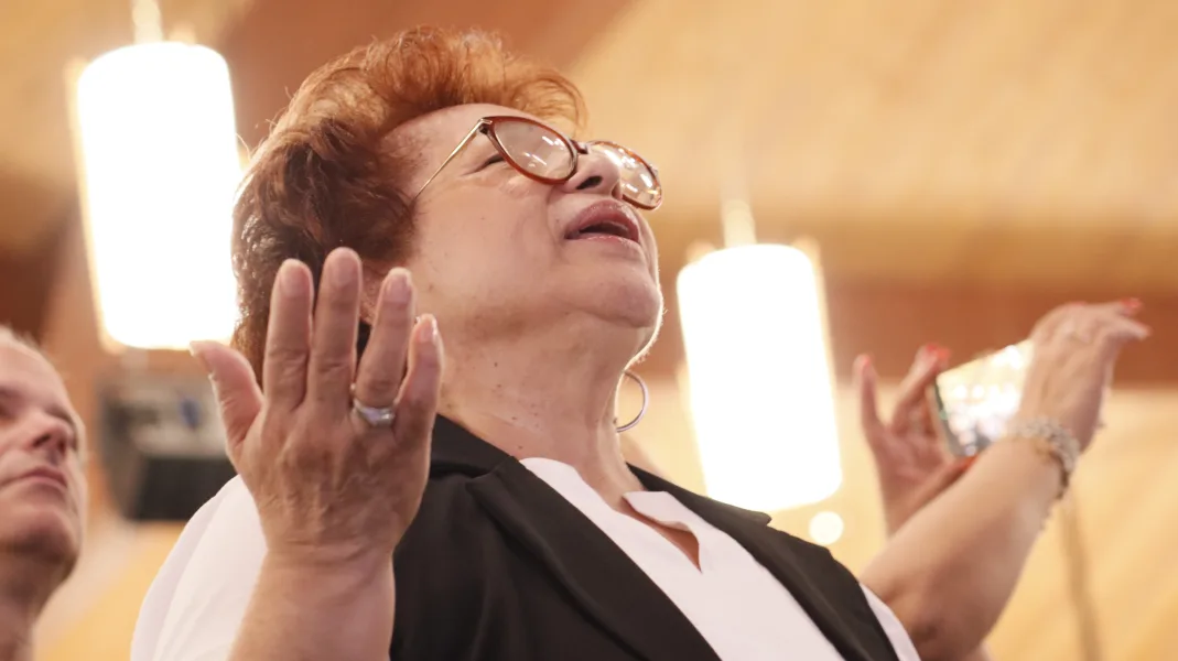 A sister prays with her eyes closed and her hands raised